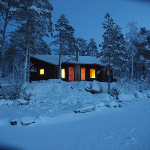 Hytte med lys i mørkt snølandskap